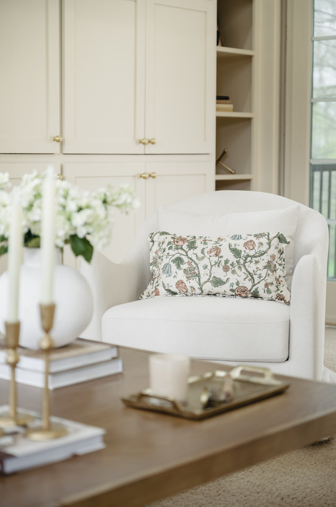a white accent chair with a floral pattern throw pillow
